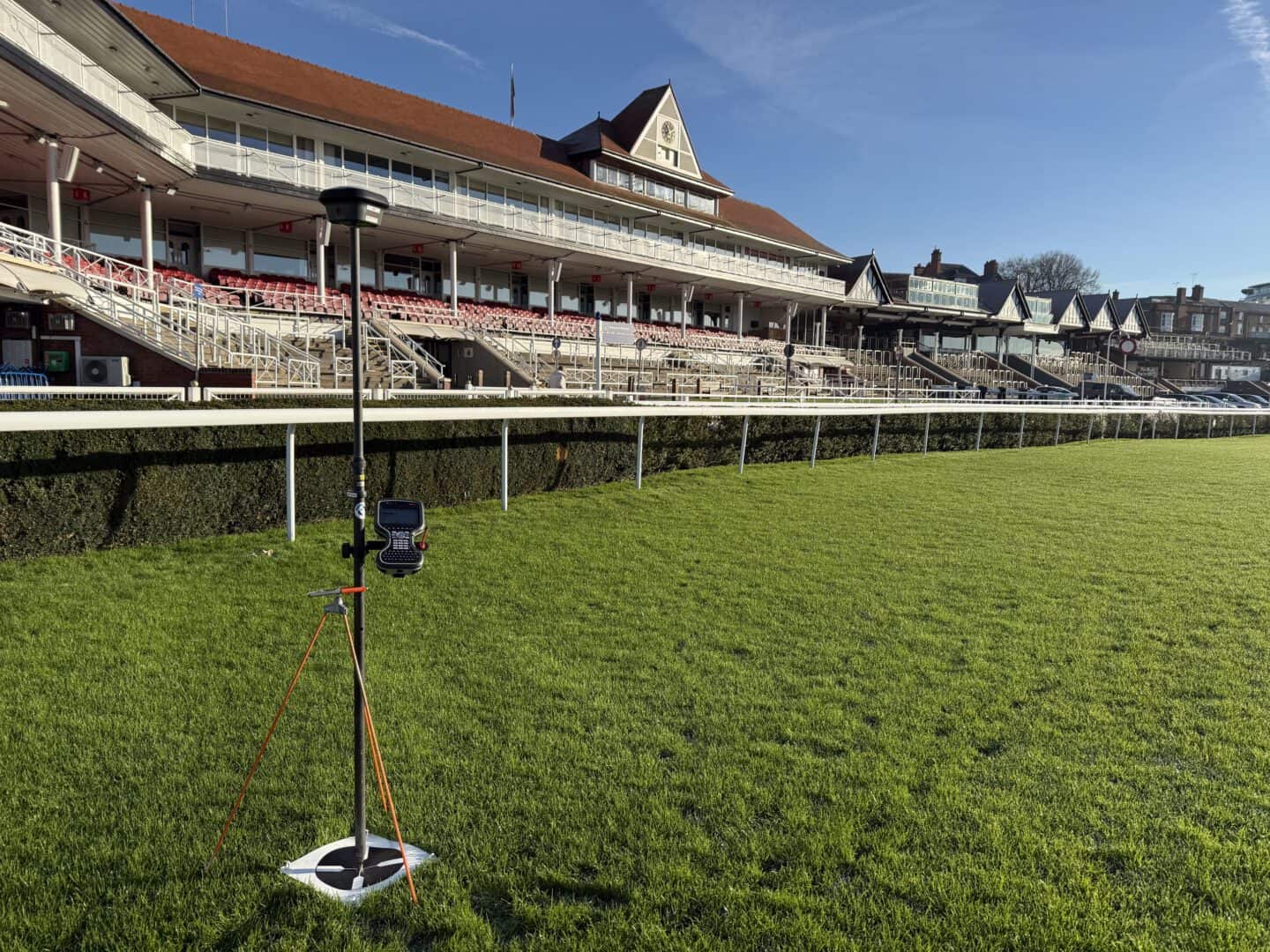 Chester Racecourse grandstand with lush green track and clear blue sky.